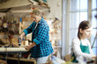 © pressmaster - Two adult female carpenters working with wood in nice workshop.