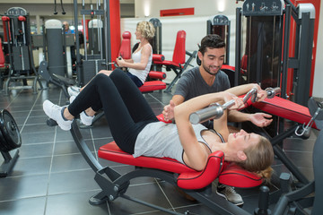 Wall Mural - male personal trainer helping young woman on her work