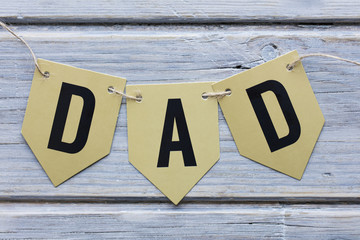 Father's Day background with a gold Dad banner on wood