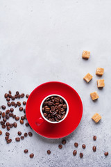 Red Cup with coffee beans inside on gray concrete background. Top view.