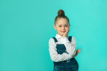 Wall Mural - beautiful little happy girl in jeans and a white shirt on a blue background