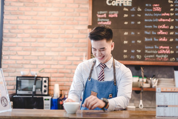 The portrait of the guy baristas at workplace on background of coffee