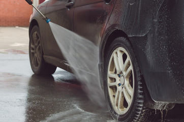 Man washing a car on the car wash self-service.