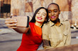 © Carlos David - Portrait two friends taking selfie while sitting at a table in an urban park