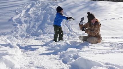 Wall Mural - Asian mother and her son playing snow together in the park , sapporo japan slow motion 