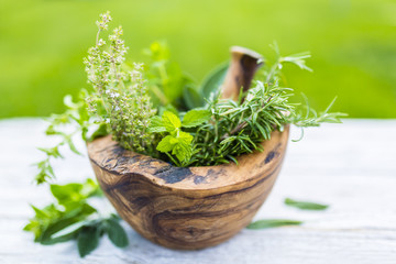 Fresh and aromatic herbs in a wooden mortar.
