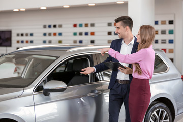 Wall Mural - Young salesman working with client in car dealership