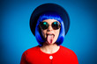 © deagreez - Head shot portrait of crazy foolish girl in headwear eyewear red outfit wig gesturing  tongue out isolated on blue background. Entertainment rest relax leisure concept