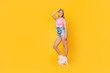 Low angle bottom view portrait of cheerful coquette pretty chick positive sportive girl riding on roller skates looking at camera isolated on yellow background
