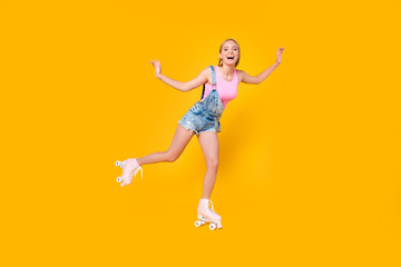 Wall Mural - Full-length portrait of glad excited girl riding on roller skates with one leg keeping balance enjoying recreation exercise isolated on yellow background, sporty fit people concept