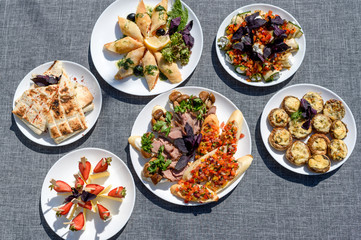 Wall Mural - Plates with snacks on servered buffet table at wedding reception outdoors, copy space. Grilled mushrooms with cheese. Sandwiches, appetizer bruschetta, antipast, crostini, tapas. top view, flat lay