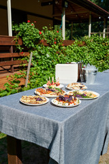 Wall Mural - Plates with snacks on servered buffet table at wedding reception outdoors, copy space. Grilled mushrooms with cheese. Sandwiches, appetizer bruschetta, antipast, crostini, tapas