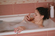 © familylifestyle - Young beautiful brunette woman takes a bath and drinks whiskey.