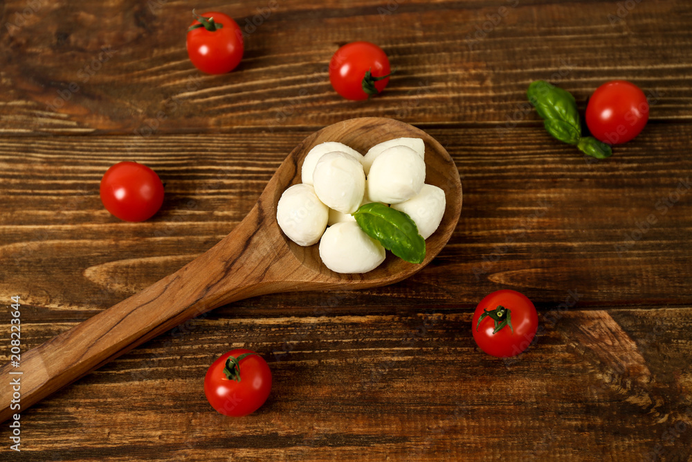 Flat lay composition with mozzarella cheese balls, cherry tomatoes and basil on wooden background
