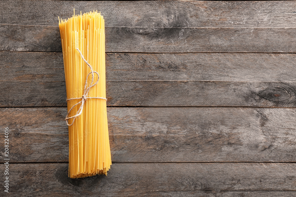 Uncooked spaghetti pasta on wooden background