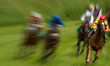 Motion blur zoom effect on race horses and jockeys turning a corner