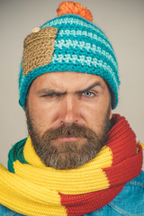 Wall Mural - Closeup portrait attractive bearded man in warm knitted hat, scarf. Health, beauty and people concept - portrait of serious caucasian man with beard in fashionable scarf and hat. Male winter fashion.