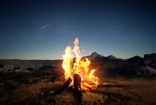 Exploring The Wilderness In Summer. A Glowing Camp Fire At Dusk Providing Comfort And Light To Appreciate Nature, Good Times And The Night Sky Full Of Stars. Photo Composite.