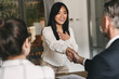 © Drobot Dean - Business, career and placement concept - two business partners in office shaking hand of young asian woman, after successful negotiations or interview
