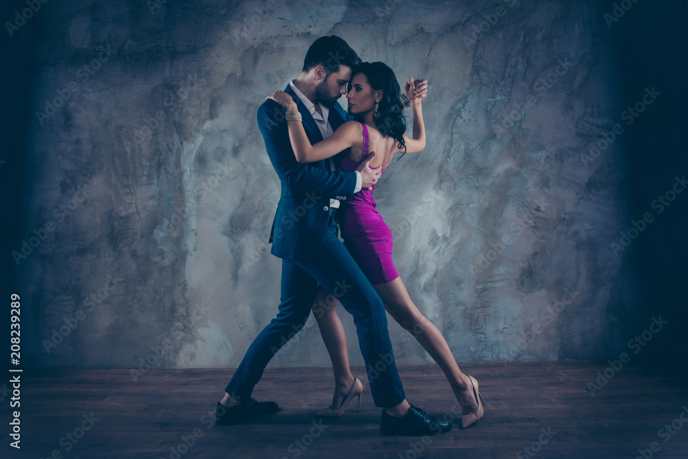 Full size body portrait of lovely attractive couple standing close in tango position face to face dancing, charming lady in purple tight dress gentlemen in tux isolated on grey background movement - obrazy, fototapety, plakaty 