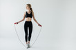 young sportive woman with skipping rope isolated on grey