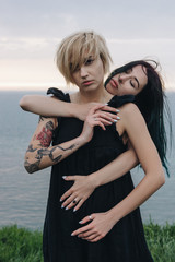 Wall Mural - beautiful young women embracing in front of ocean on cloudy day