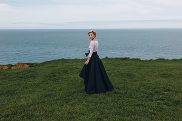 Wall Mural - elegant young woman posing on majestic cliff, Etretat, Normandy, France