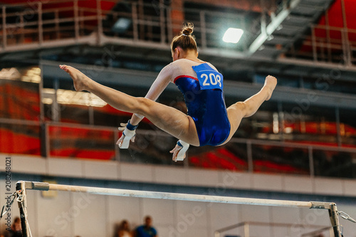 Fotografía women gymnast exercises on uneven bars in artistic gymnastics