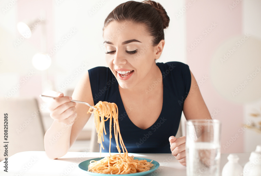 Young woman eating tasty pasta in cafe