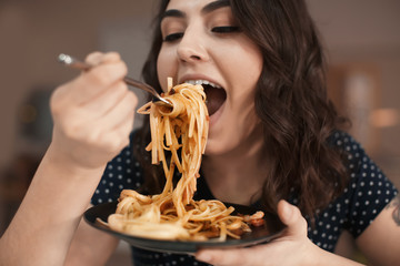 Young woman eating tasty pasta in cafe