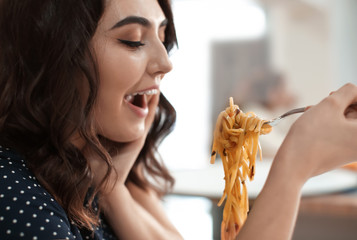 Young woman eating tasty pasta in cafe