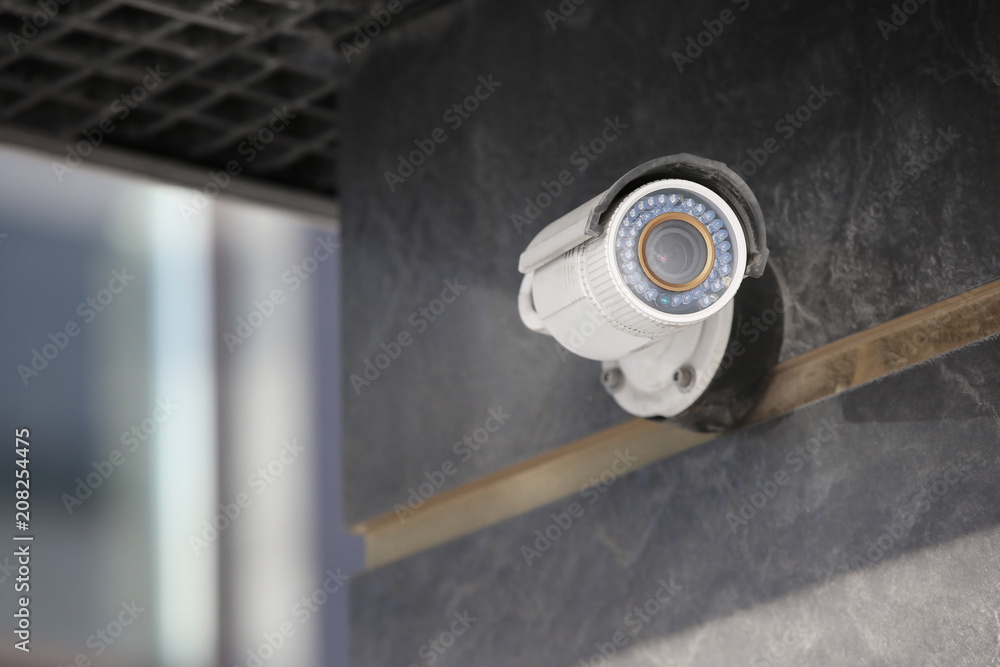 Modern CCTV camera on wall of building outdoors