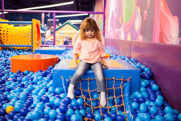 Happy little girl child in colourful blue plastic balls pool.