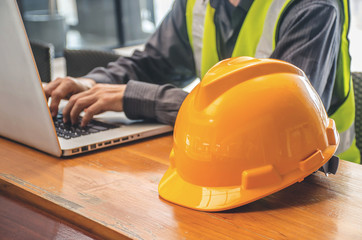 The yellow safety helmet and Business man in Construction industry is working in on computer on the background.