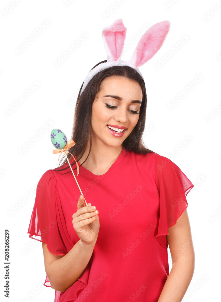 Beautiful young woman with Easter egg and bunny ears on white background