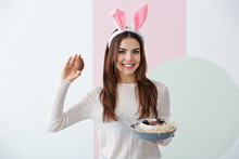 Beautiful Young Woman With Chocolate Easter Eggs And Bunny Ears On Color Background