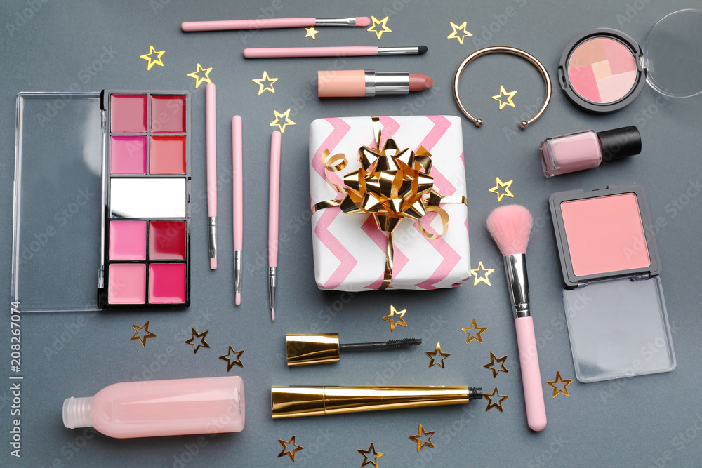 Composition with gift box and set of decorative cosmetics on grey background, flat lay