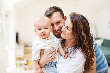 young family with a baby boy at home, standing and posing for the photo.