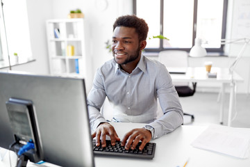 business, people and technology concept - african american businessman with computer working at office