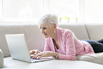 Retired senior woman sitting at home using her laptop