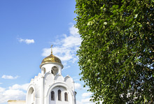 Golden Dome Of A Church Against A Blue Sky And Green Leaves