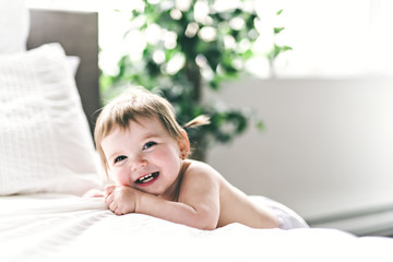 one years girl baby on the side of the bed