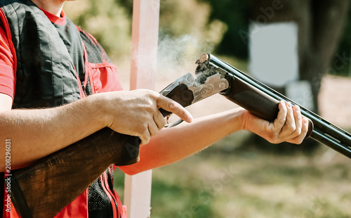 Fotomural man opens the shotgun bolt after one shot with smoke