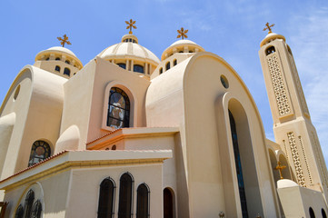 A large Egyptian orthodox white church with crosses, arches, domes and windows for prayers.