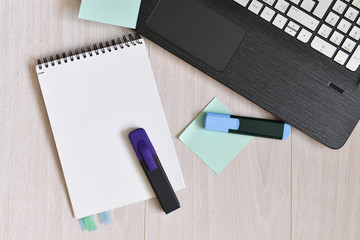 table with a laptop and blaknotom. A blank page for entering text in the middle.