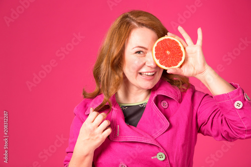 Beautiful adult woman holding one half of juicy grapefruit covering her eye Poster
