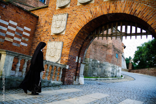 Zdjęcie XXL Brama wjazdowa do Zamku Królewskiego na Wawelu w Krakowie. Mniszka w czarnym habicie idzie do zamku