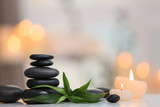 Stack of spa stones and burning candles on blurred background