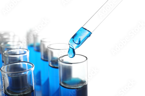 Dripping blue liquid into test tubes on white background