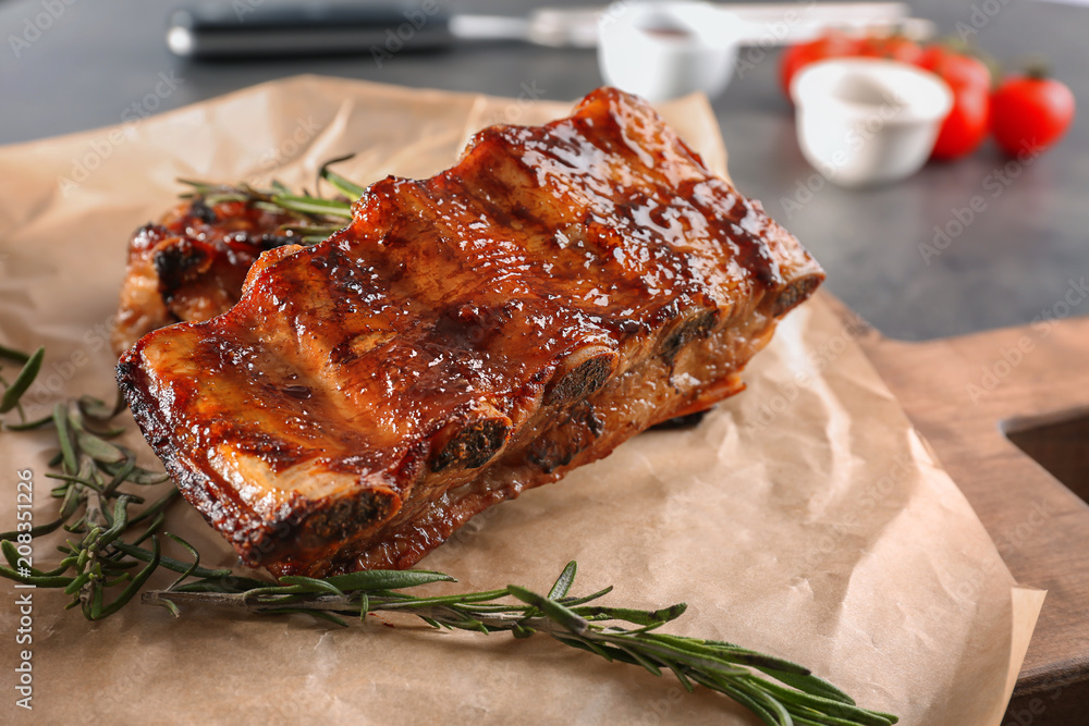 Delicious grilled ribs with rosemary on parchment, closeup